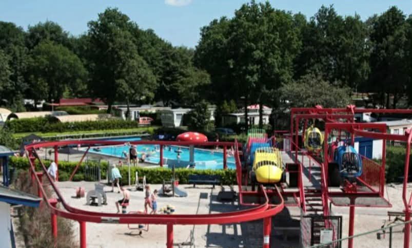Overzicht van het buitenzwembad en het speelplein op de camping